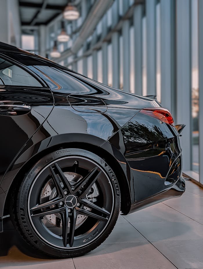 Black luxury sedan with distinctive emblem and shiny alloy wheels parked indoors. Perfect for car enthusiasts.